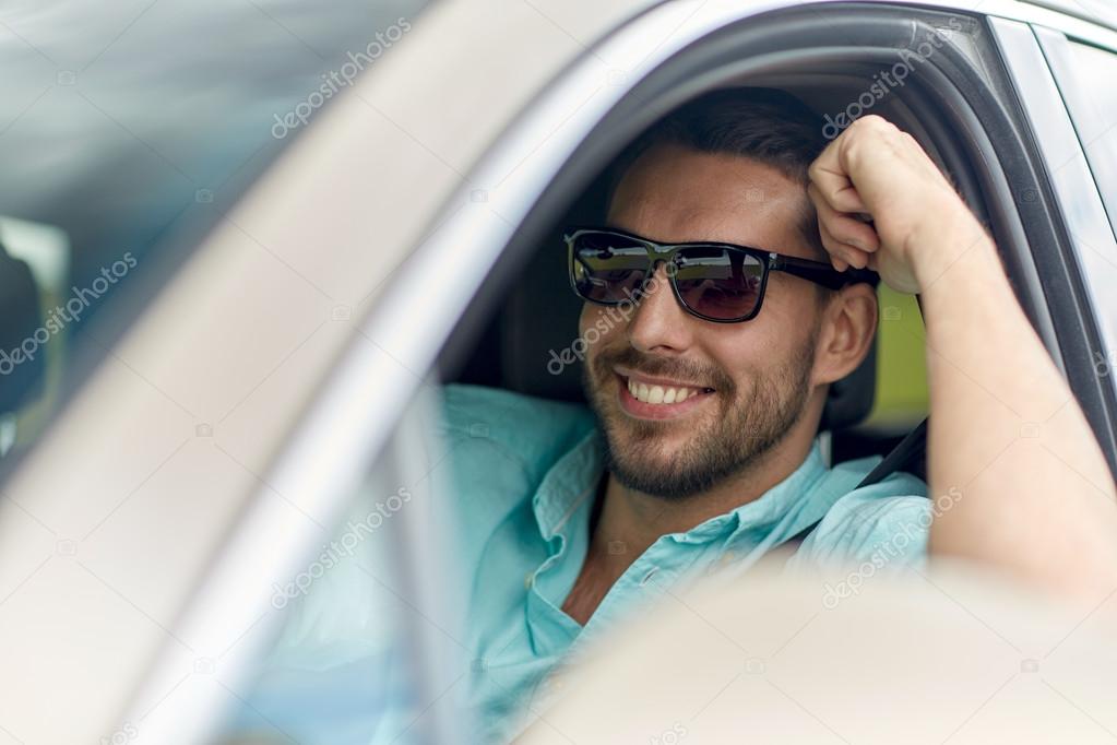 Happy smiling man in sunglasses driving car — Stock Photo