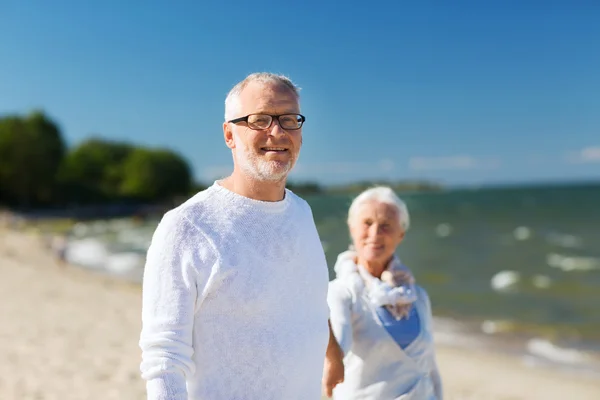 Gelukkige senior paar bedrijf handen op zomer strand — Stockfoto