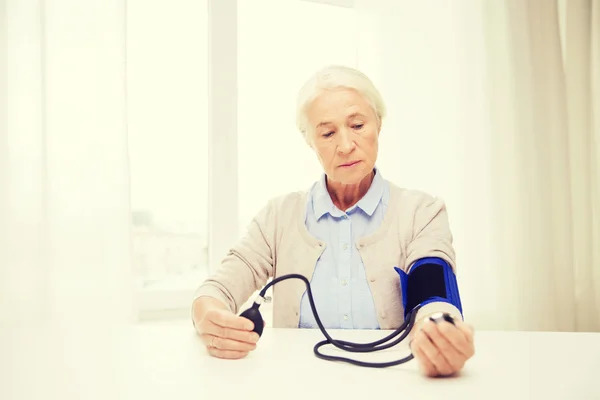 Old woman with tonometer checking blood pressure — Stock Photo, Image