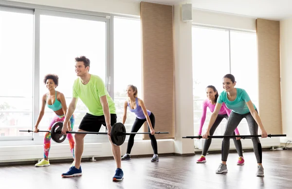 Personnes heureuses faisant de l'exercice avec des barres d'haltères dans la salle de gym — Photo