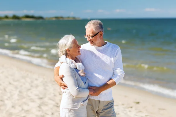 Счастливая пожилая пара, держащаяся за руки на летнем пляже — стоковое фото
