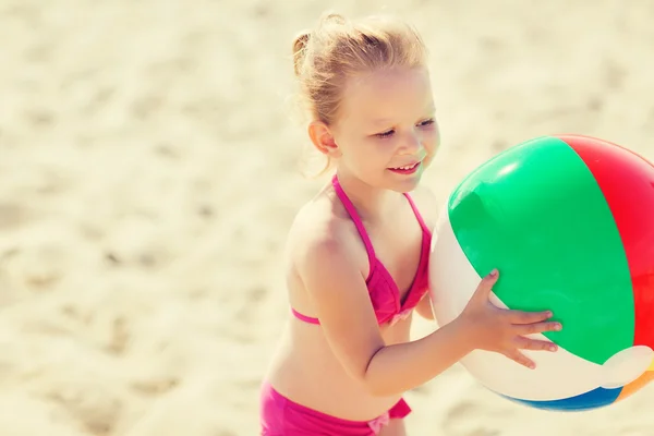 Heureuse petite fille jouant ballon gonflable sur la plage — Photo