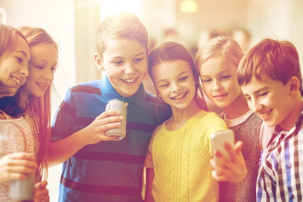 Grupo de niños de la escuela con teléfonos inteligentes y latas de refrescos — Foto de Stock