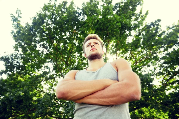 Sporty young man with crossed arms at summer park — Stock Photo, Image