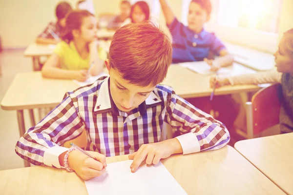 Grupp av skolbarnen skriva prov i klassrummet — Stockfoto