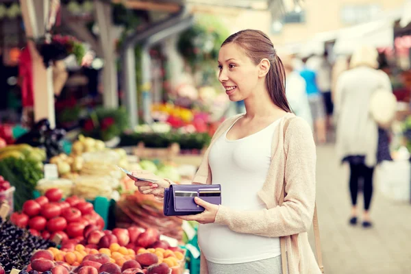 Mujer embarazada con billetera comprando alimentos en el mercado — Foto de Stock