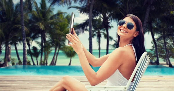 Lachende vrouw met tablet pc om te zonnebaden op het strand — Stockfoto