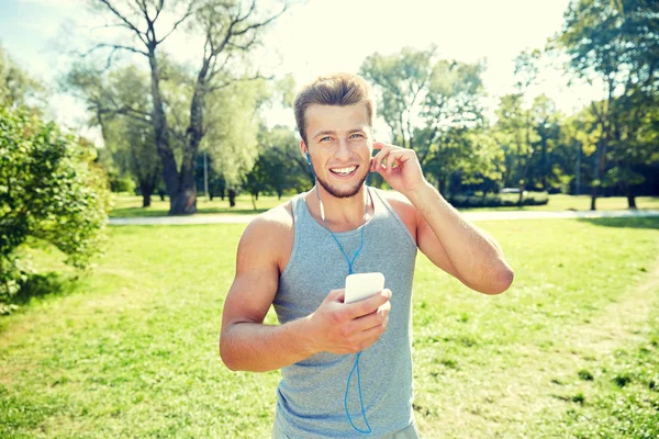 Homme heureux avec écouteurs et smartphone au parc — Photo