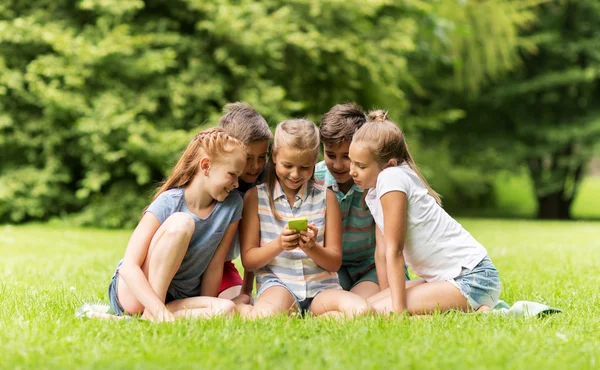 Niños o amigos con smartphone en el parque de verano —  Fotos de Stock
