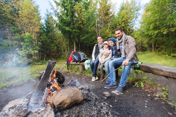 Família feliz sentado no banco no acampamento fogo Fotos De Bancos De Imagens Sem Royalties