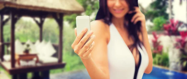 Woman taking selfie with smartphone over bungalow — Stock Photo, Image