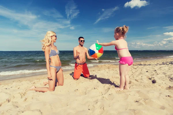 Família feliz que joga com bola inflável na praia — Fotografia de Stock