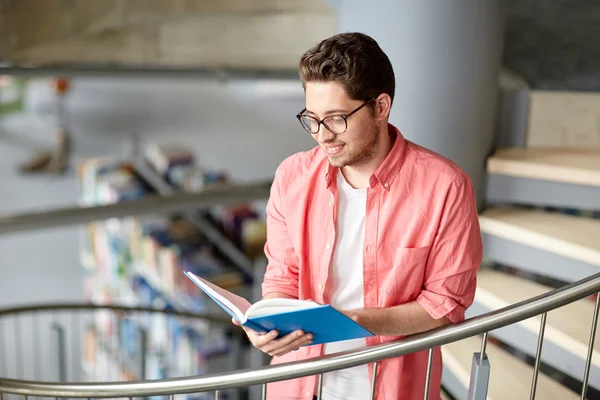 Студент или молодой человек, читающий книги в библиотеке — стоковое фото
