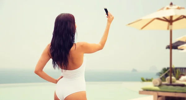 Genç bir kadın sahilde akıllı telefonuyla selfie çekiyor. — Stok fotoğraf