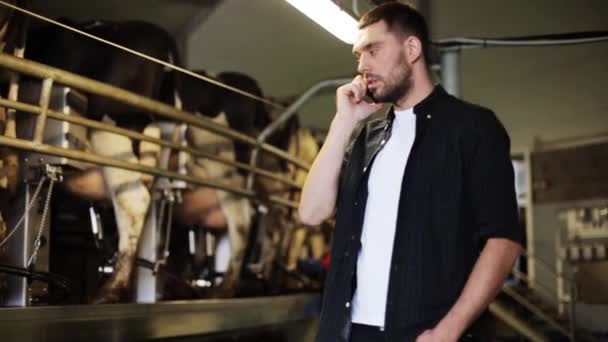 Homme appelant sur téléphone cellulaire et vaches à la ferme laitière — Video