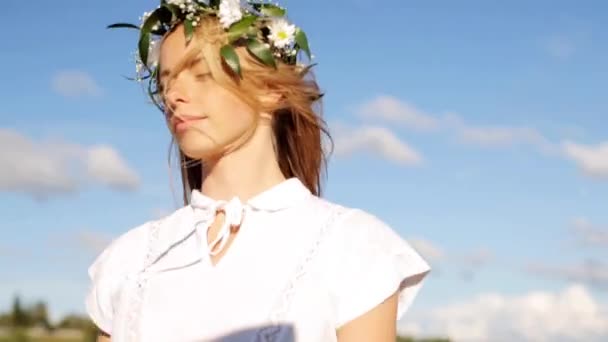 Jonge vrouw in een krans van bloemen buiten glimlachen — Stockvideo