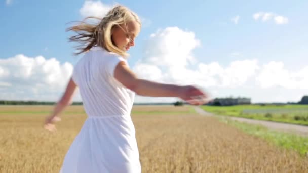 Lächelnde junge Frau im weißen Kleid auf einem Getreidefeld — Stockvideo