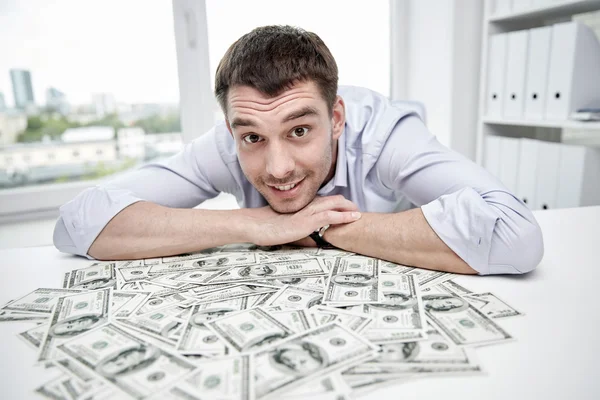 オフィスでお金のヒープを持つ幸せなビジネスマン — ストック写真