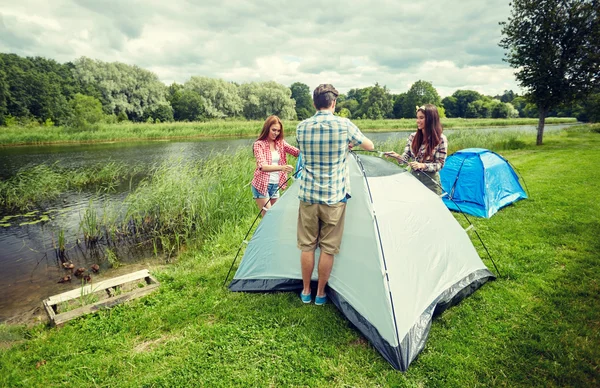 Group of smiling friends setting up tent outdoors — Stock Photo, Image