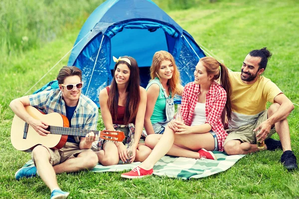 Amigos felizes com bebidas e guitarra no acampamento — Fotografia de Stock