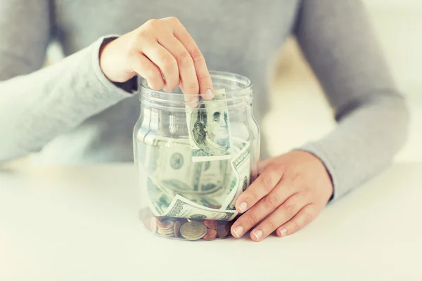 Close up de mãos de mulher e dinheiro dólar em jarra — Fotografia de Stock