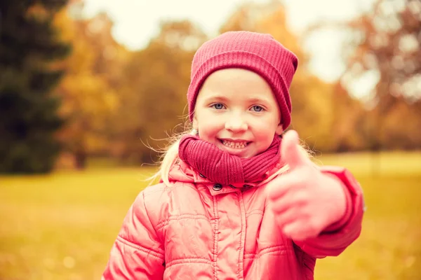 Happy little girl showing thumbs up in autumn park — Stok fotoğraf