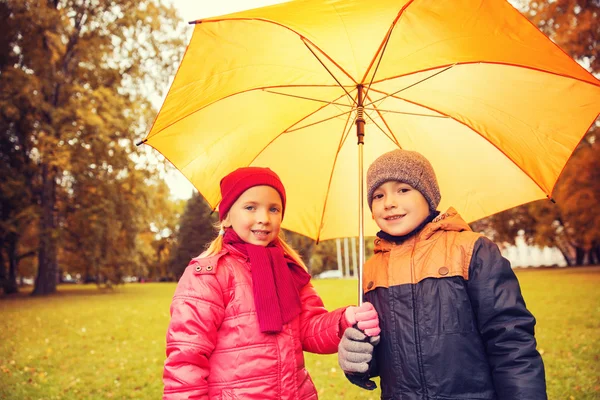 Feliz niño y niña con paraguas en el parque de otoño Imágenes De Stock Sin Royalties Gratis