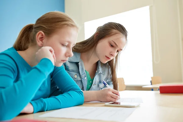 Student girls with smartphone writing school test — Stock Photo, Image