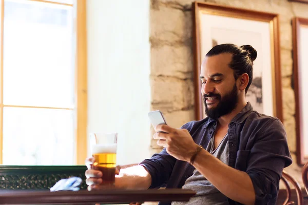 Mann mit Smartphone trinkt Bier in Bar oder Kneipe — Stockfoto