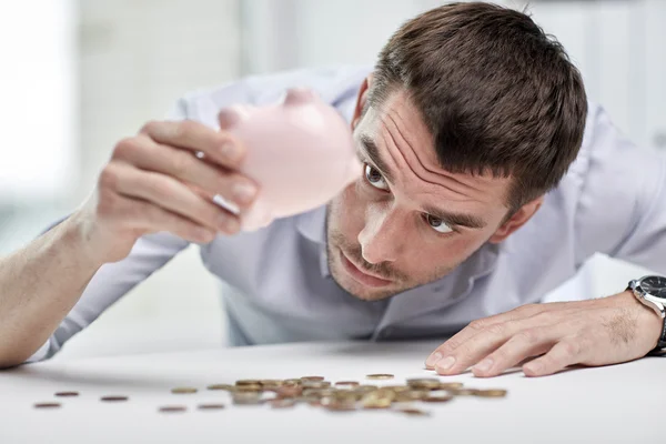 Affärsman med spargris och mynt på kontor — Stockfoto