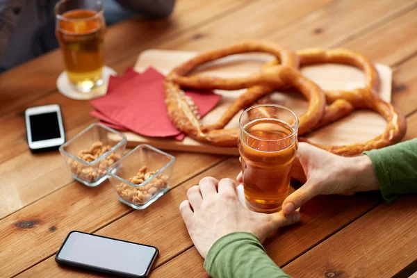 Närbild av händer med smartphones och öl på bar — Stockfoto