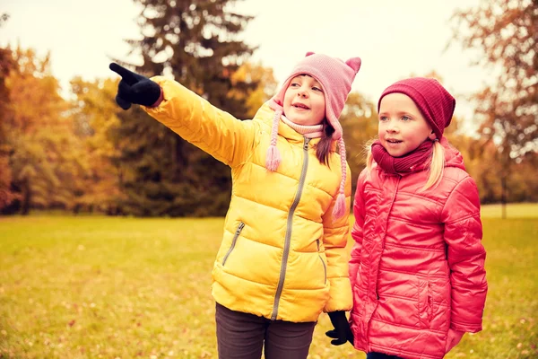 Happy little girls pointing finger in autumn park — Zdjęcie stockowe