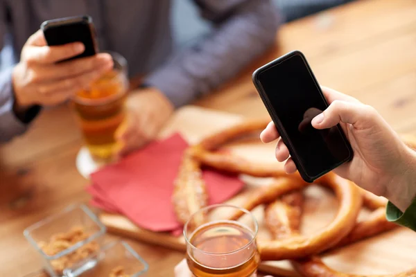 Primo piano delle mani con smartphone e birra al bar — Foto Stock