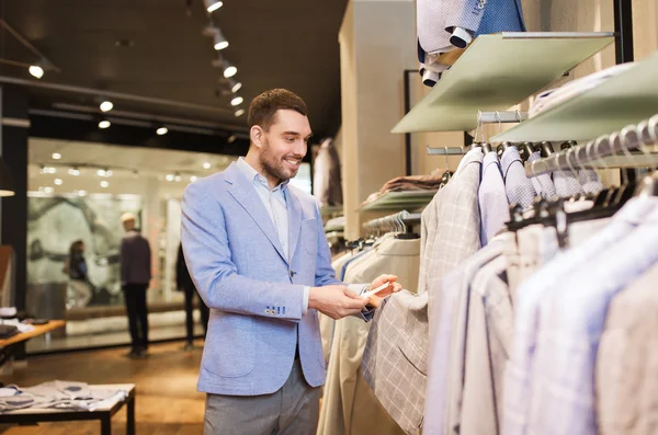 Glad ung man väljer kläder i klädaffär — Stockfoto