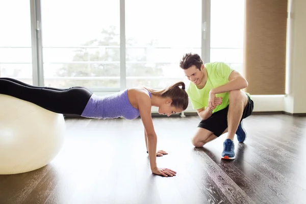 Smiling man and woman with exercise ball in gym — Stock Photo, Image