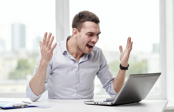 Wütender Geschäftsmann mit Laptop und Papieren im Büro — Stockfoto
