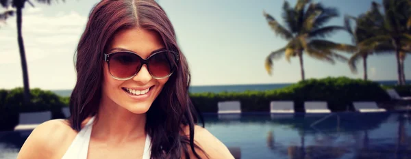 Sorrindo jovem mulher com óculos de sol na praia — Fotografia de Stock