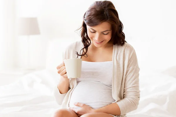 Heureuse femme enceinte avec tasse boire du thé à la maison — Photo