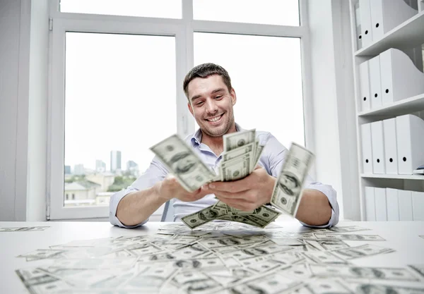 Hombre de negocios feliz con un montón de dinero en la oficina —  Fotos de Stock