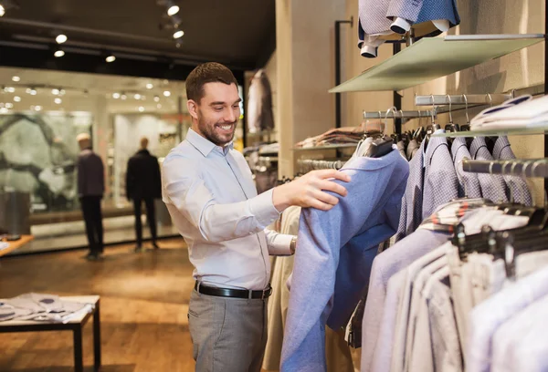 Šťastný mladý muž výběru oblečení v obchod s oblečením Stock Snímky