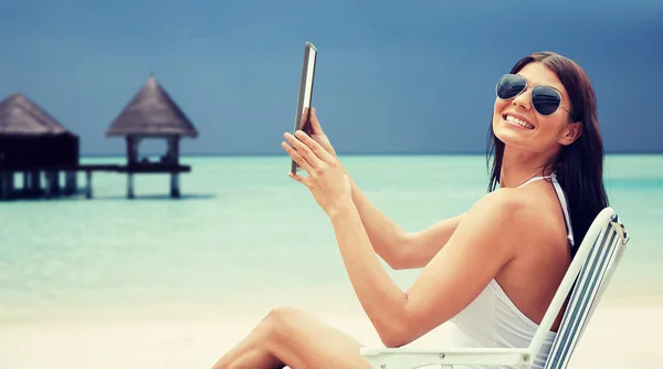 Mulher sorridente com tablet pc banhos de sol na praia — Fotografia de Stock