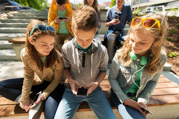 Amigos adolescentes felices con teléfonos inteligentes al aire libre —  Fotos de Stock