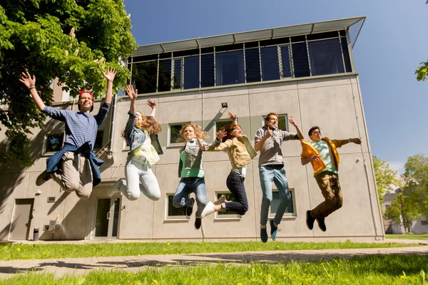 Happy teenage students or friends jumping outdoors — Stock Photo, Image