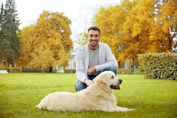Счастливый человек с собакой лабрадор в осеннем городском парке — стоковое фото