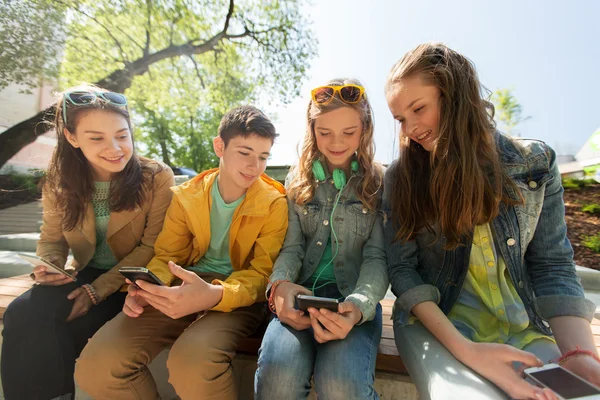 Gelukkig jeugdvrienden met smartphones outdoors — Stockfoto