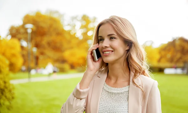 Uśmiechający się młoda kobieta, wywołanie na smartphone na zewnątrz — Zdjęcie stockowe