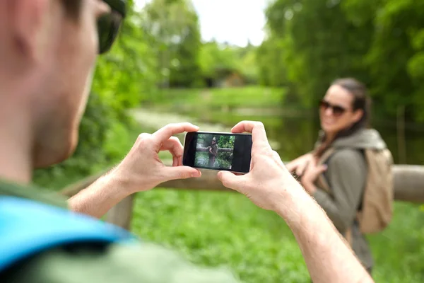 Couple with backpacks taking picture by smartphone — Stock Photo, Image