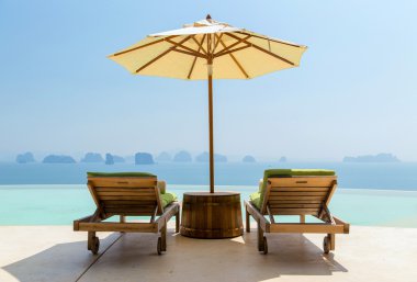 infinity pool with parasol and sun beds at seaside clipart