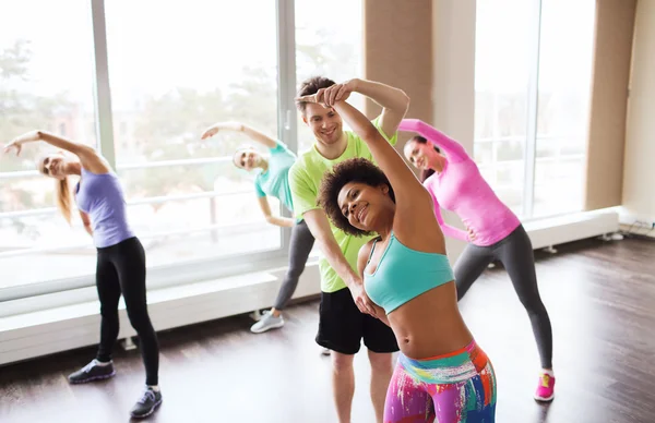 Grupo de personas sonrientes estirándose en el gimnasio — Foto de Stock