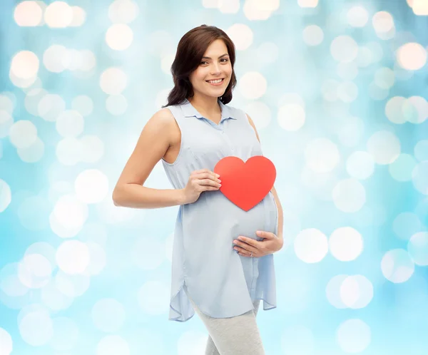 Glückliche schwangere Frau mit rotem Herz, das den Bauch berührt — Stockfoto